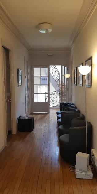 Couloir d’accueil du cabinet, avec des fauteuils et une porte vitrée